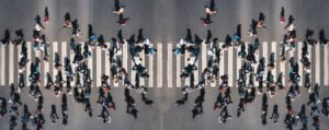 Different people at a pedestrian crossing in the city - panorama shot. People at a zebra pedestrian crossing - a lot of pedestrians in an overcrowded city on a sunny day. Aerial drone banner shot.